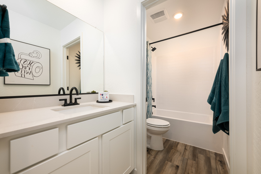 A bathroom with a sink toilet and mirror.