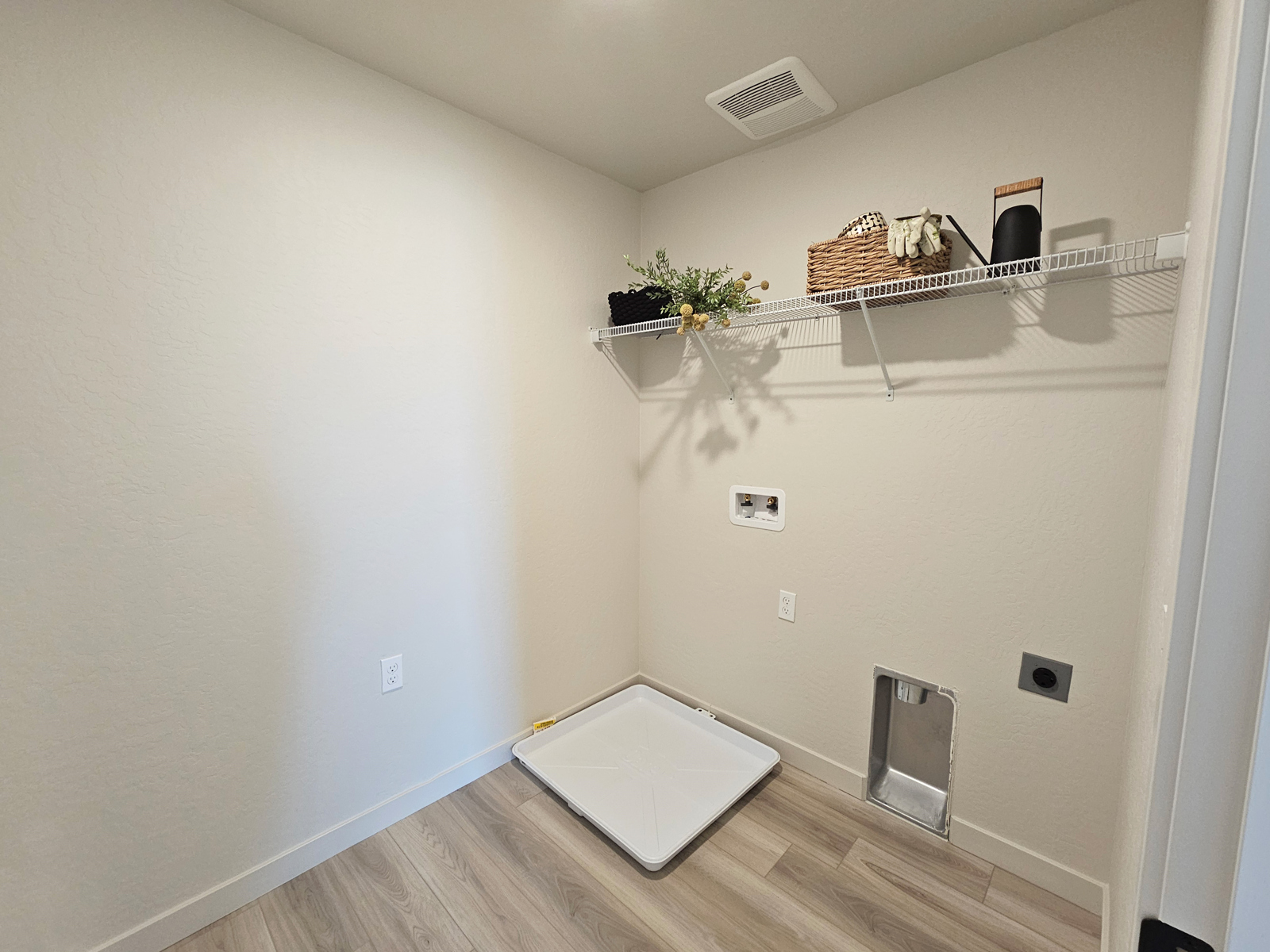 A room with a shelf and a basket on the wall.