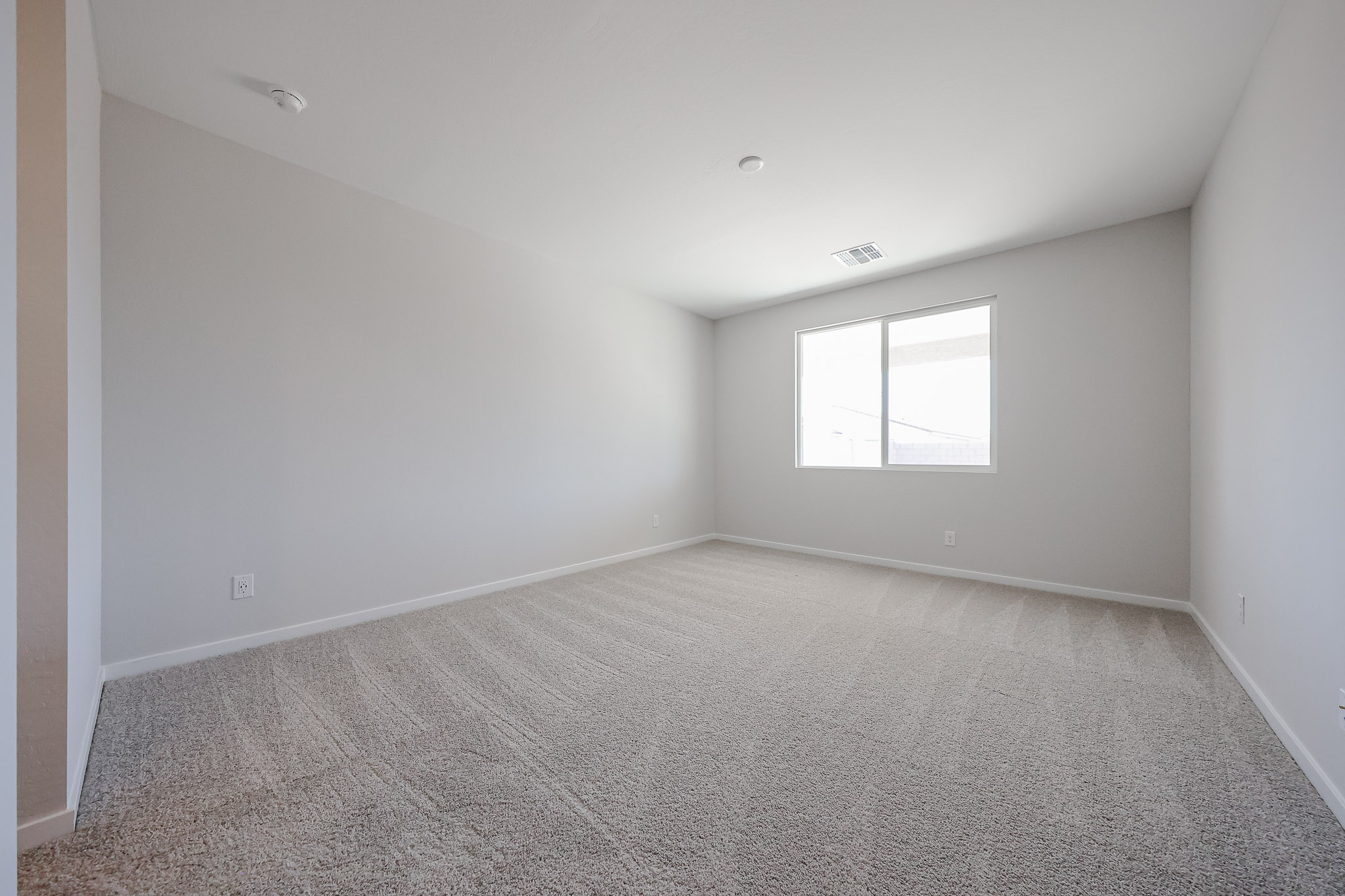 A room with a carpet and a window.