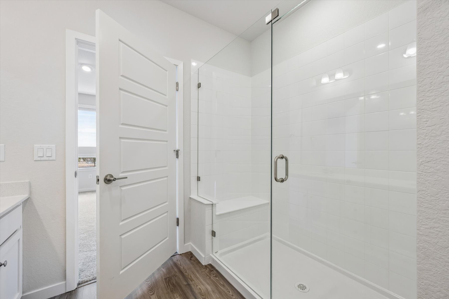A bathroom with a shower unit and a glass door.