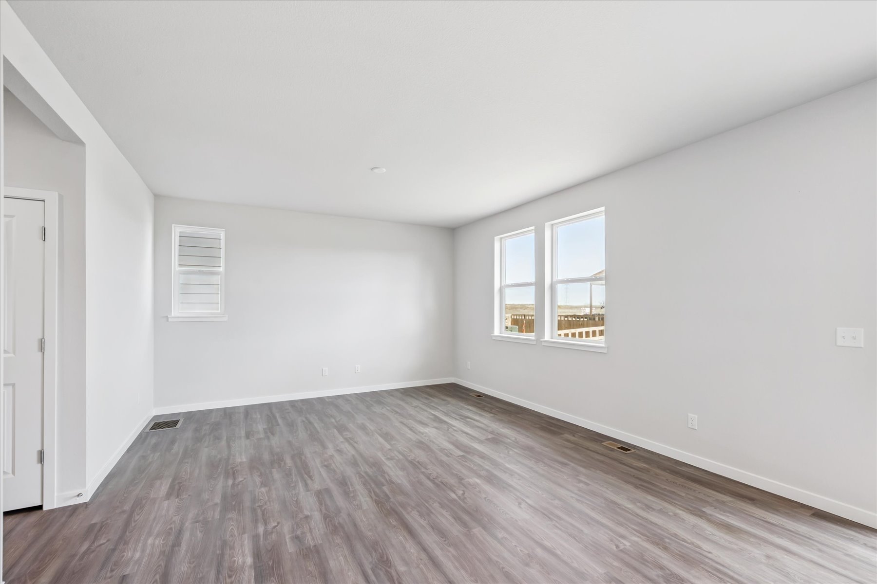 A room with a wood floor and windows.