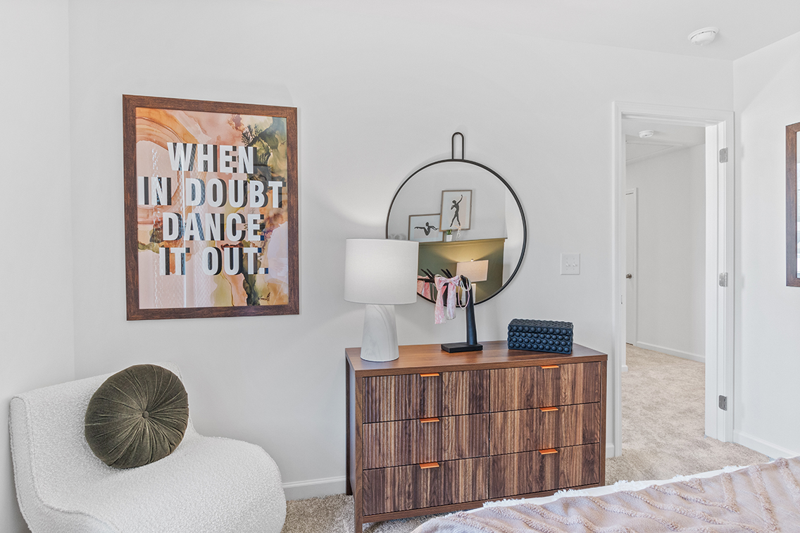 A room with a mirror and a dresser.
