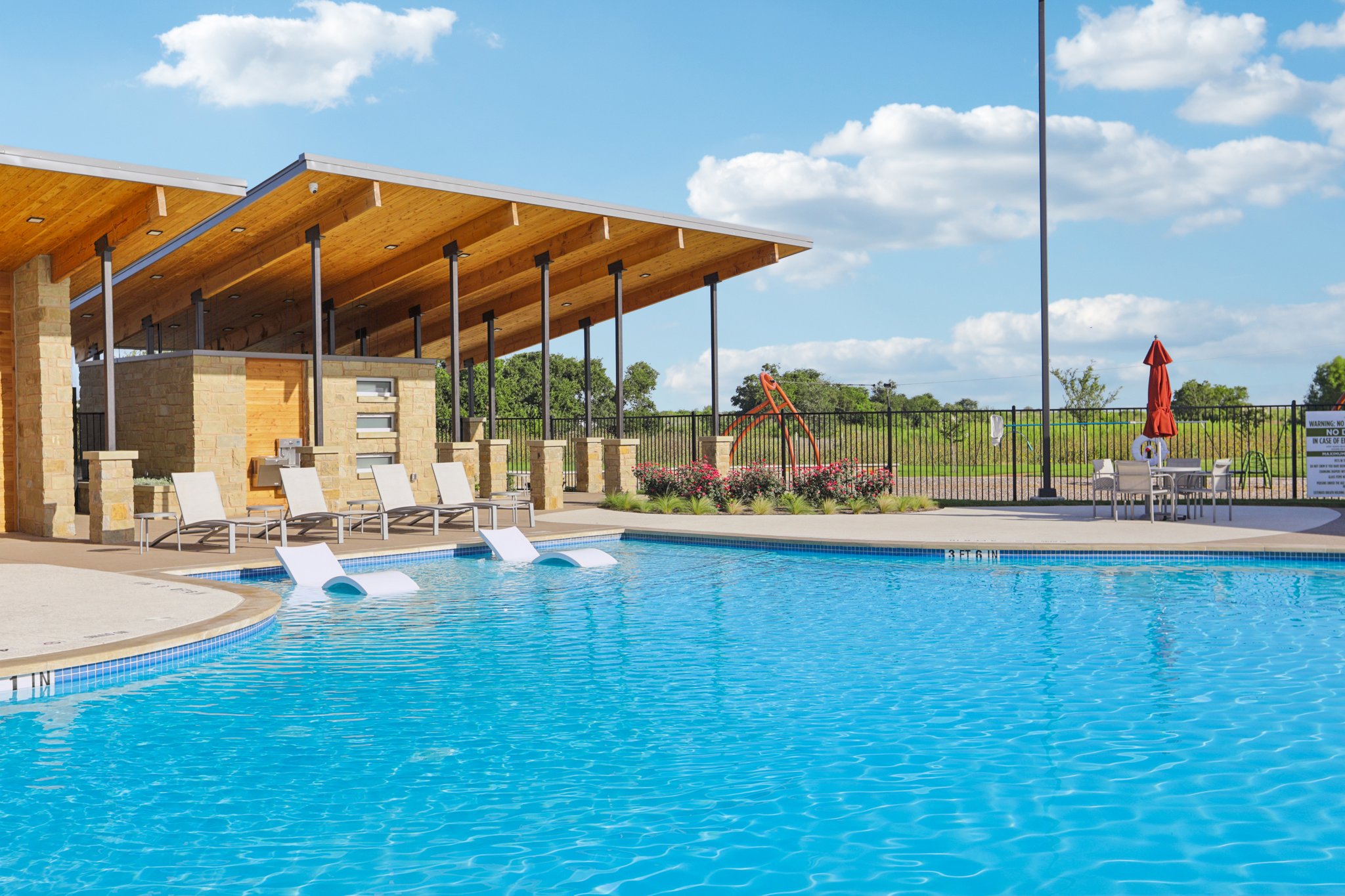 A swimming pool with chairs and umbrella.