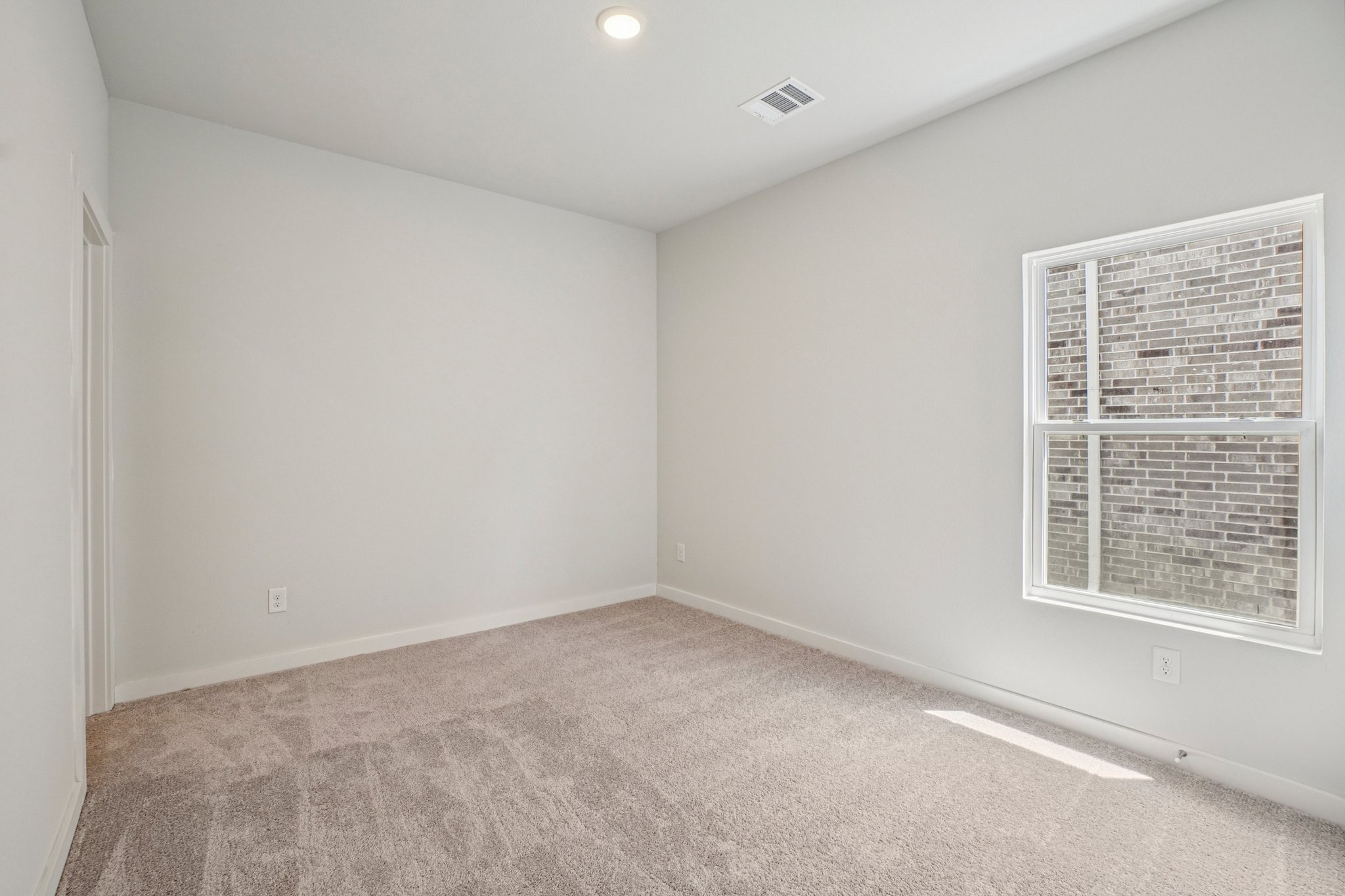 A room with a carpet and a window.