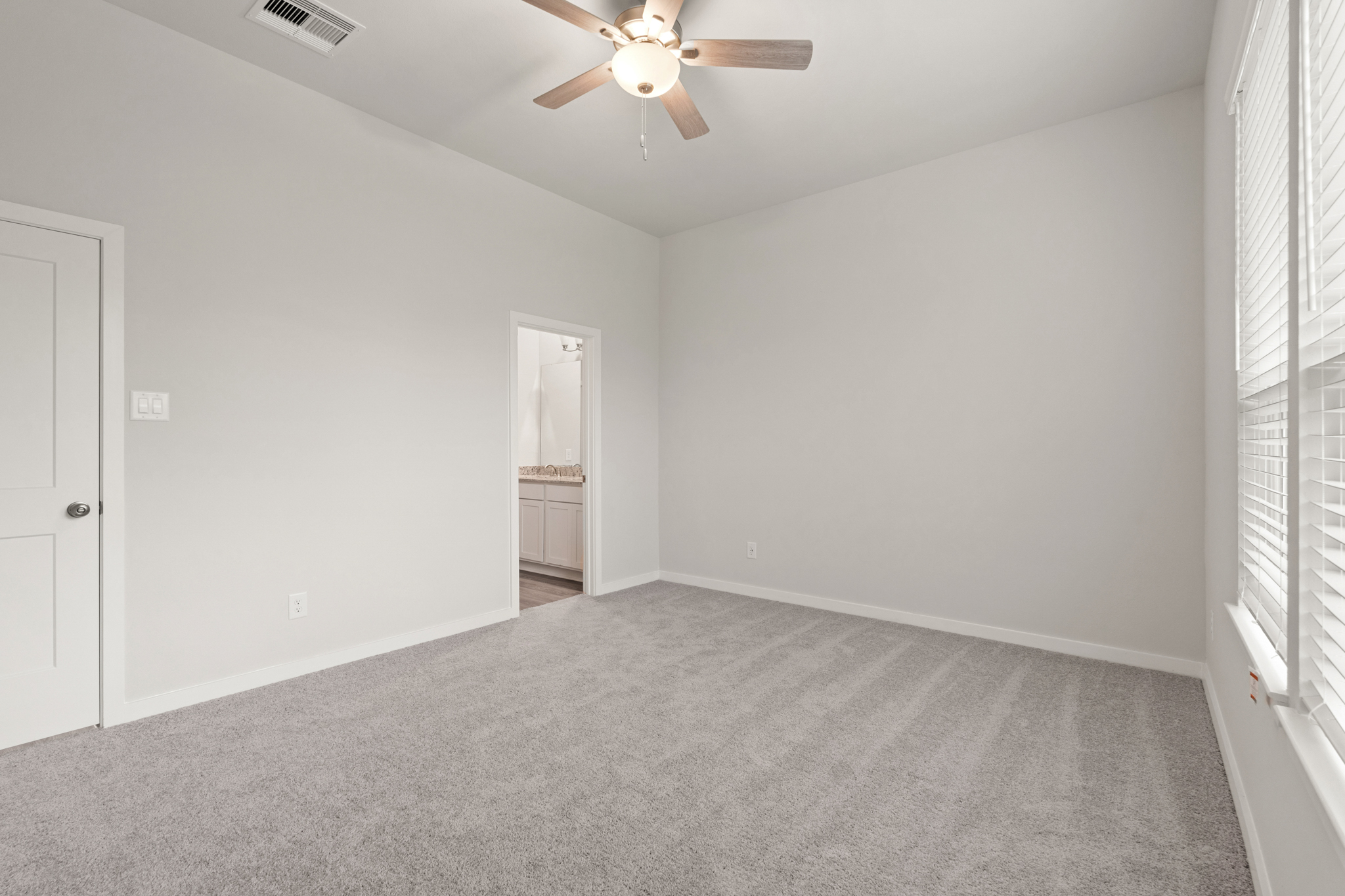 A room with a ceiling fan and a door.