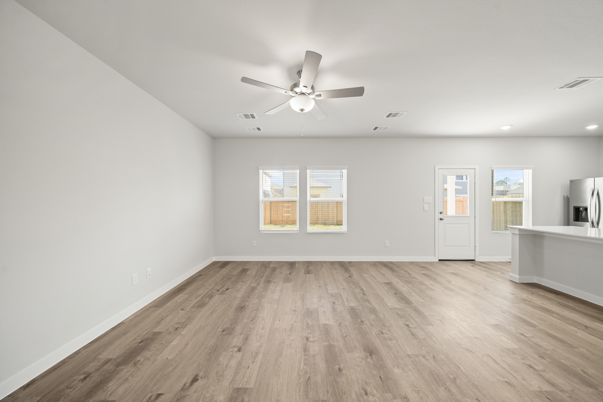 A room with a ceiling fan and a wood floor.