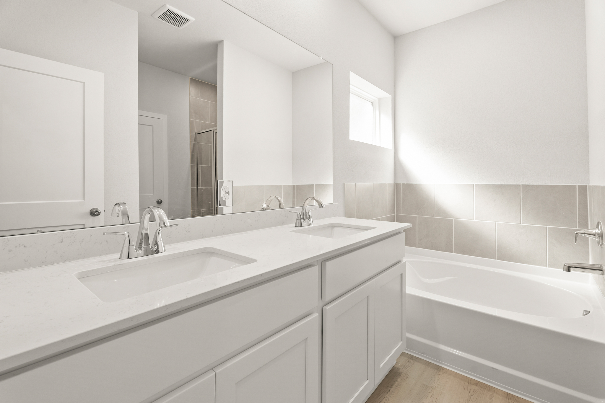 A bathroom with a tub sink and mirror.