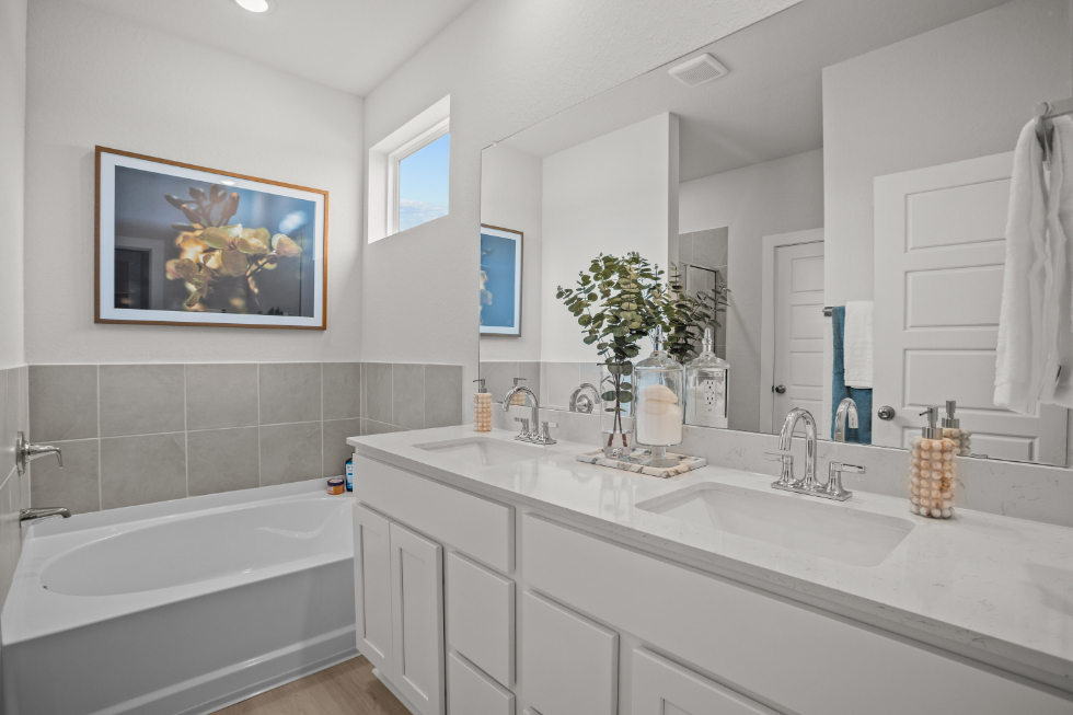 A bathroom with a tub sink and a mirror.