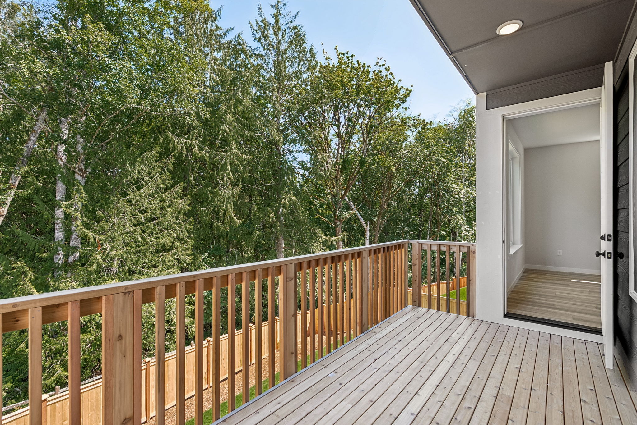 A deck with a wood railing and trees in the background.