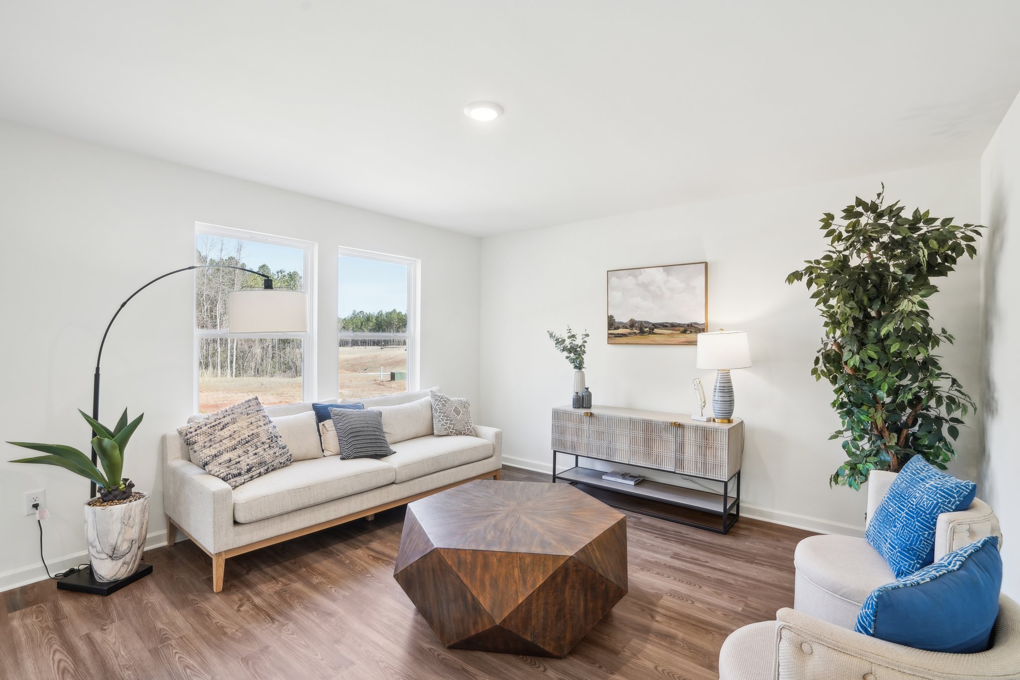 A living room with a white couch and blue pillows.